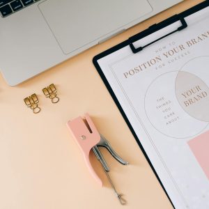 A flat lay composition featuring office essentials and a branding strategy clipboard on a modern workspace.