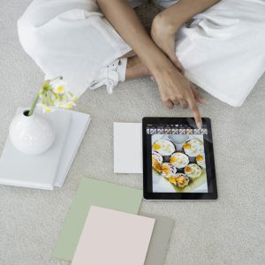 Young woman using a tablet in a modern, minimalist workspace with pastel decor.